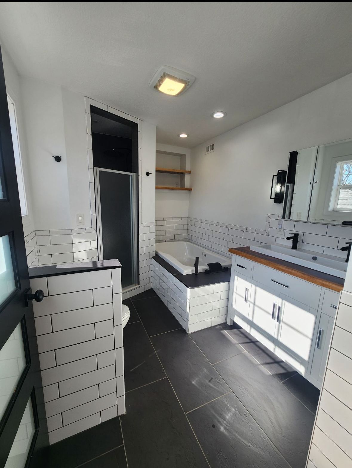 A bathroom with a tub , sink , mirror and shower.