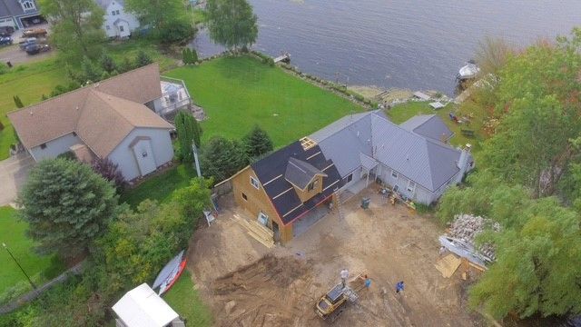 An aerial view of a house under construction next to a body of water.