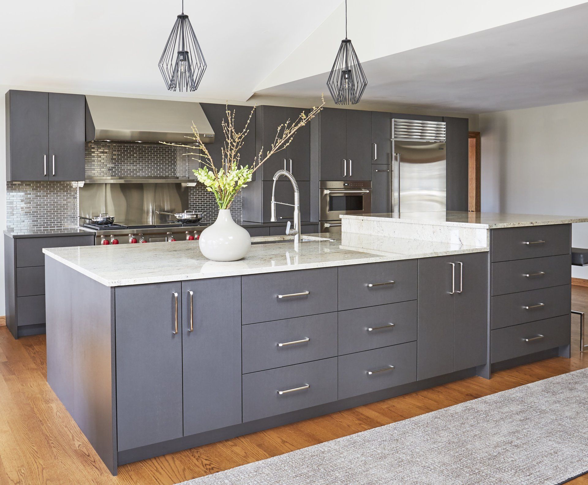 A kitchen with a large island and a vase of flowers on the counter.