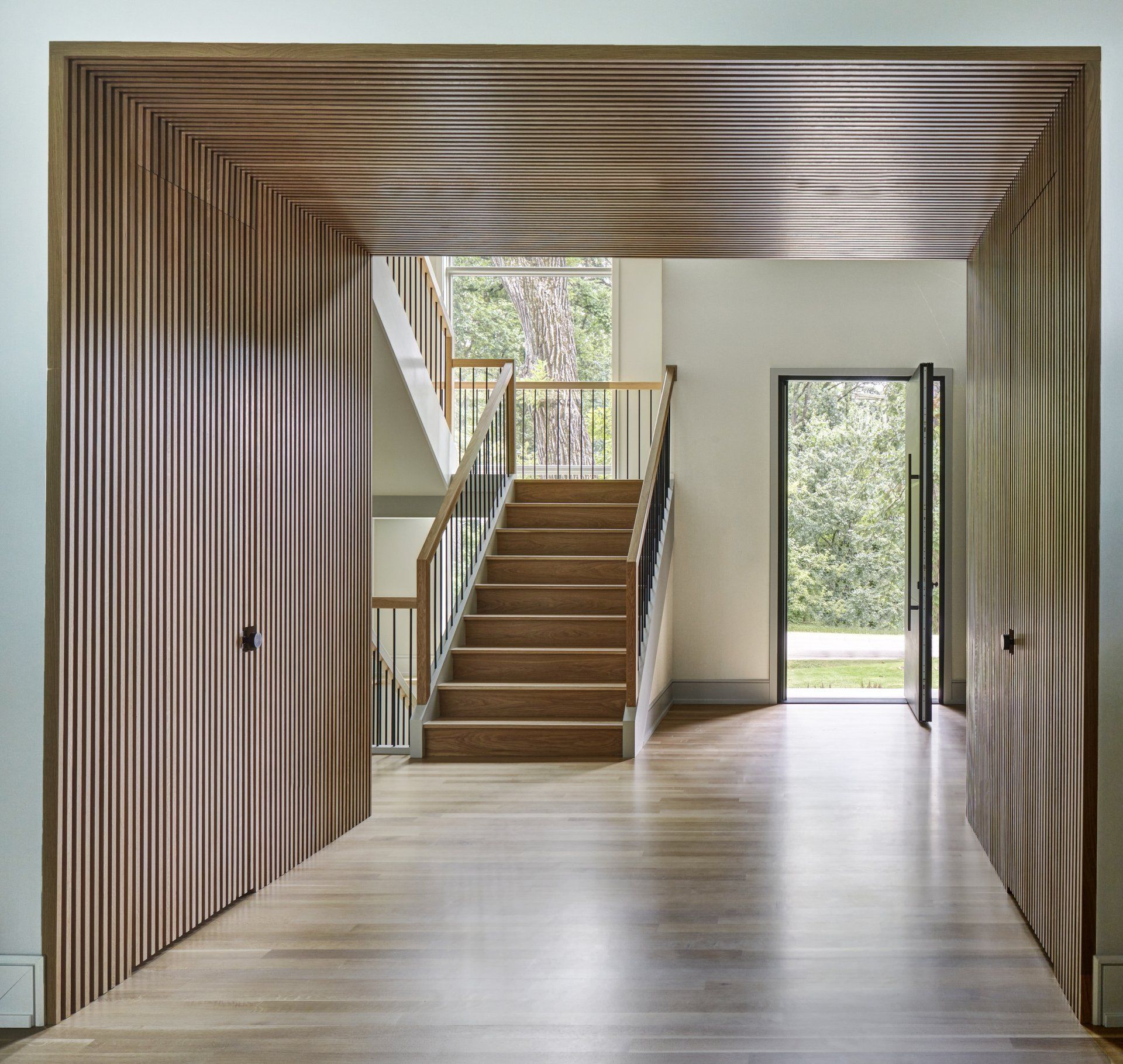 A hallway with a wooden staircase and a door