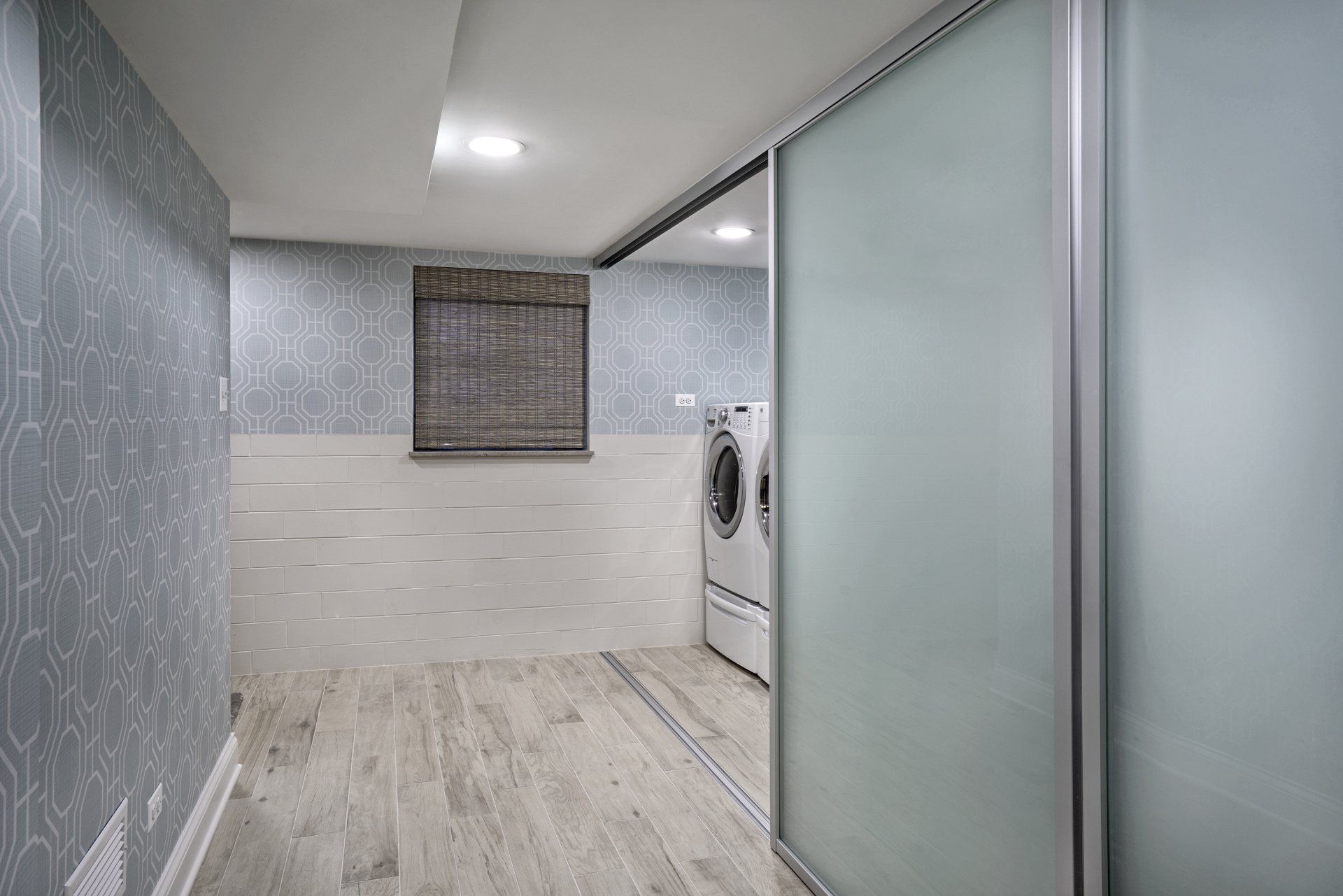 A laundry room with a washer and dryer and sliding glass doors.
