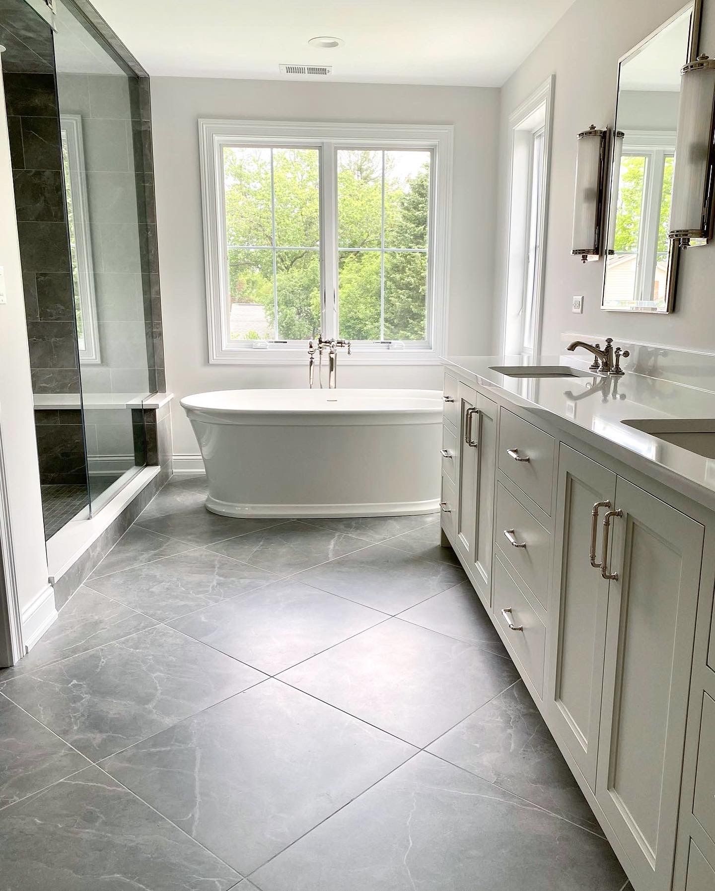 A bathroom with a tub , sink , mirror and window.