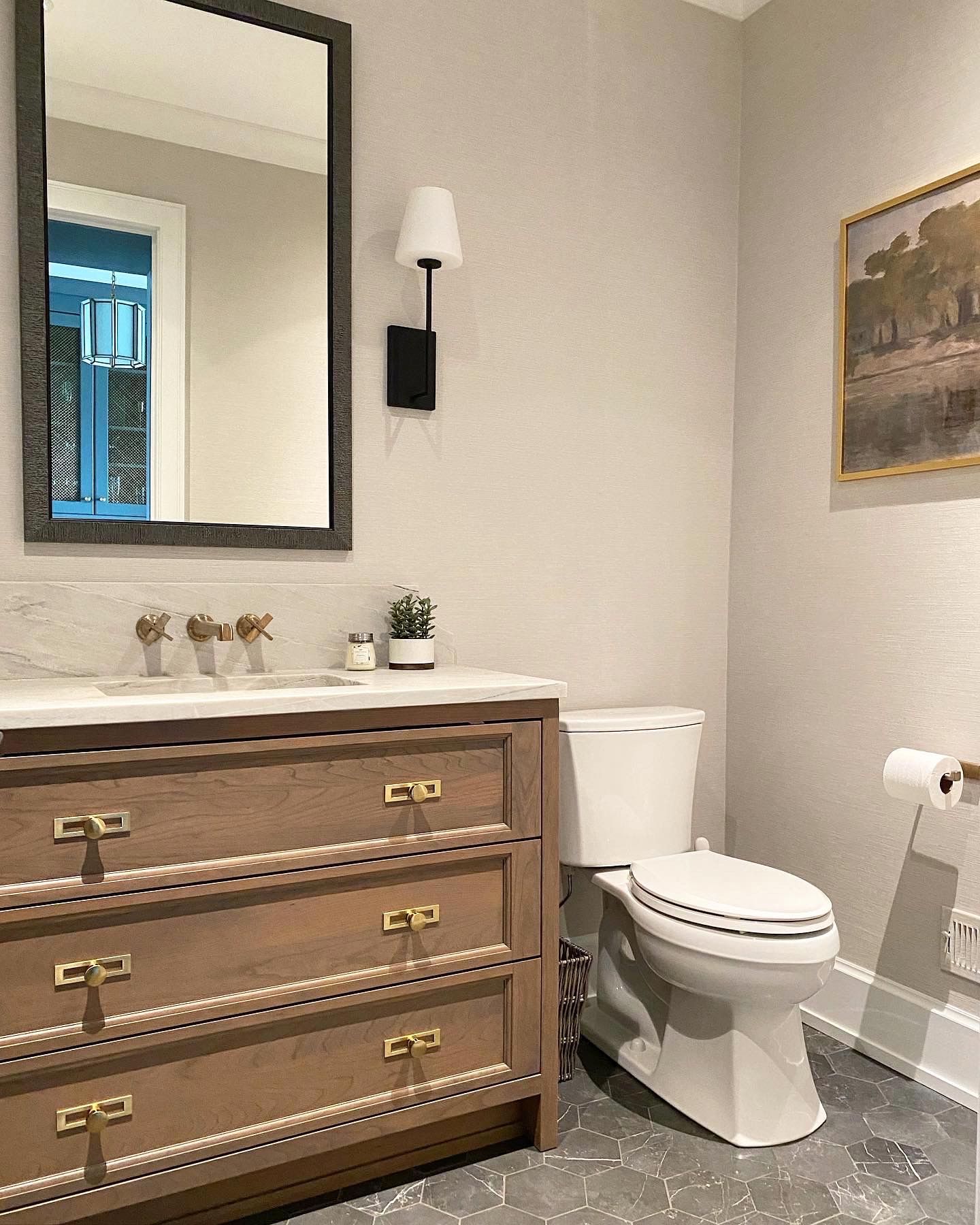 A bathroom with a toilet , sink , mirror and dresser.