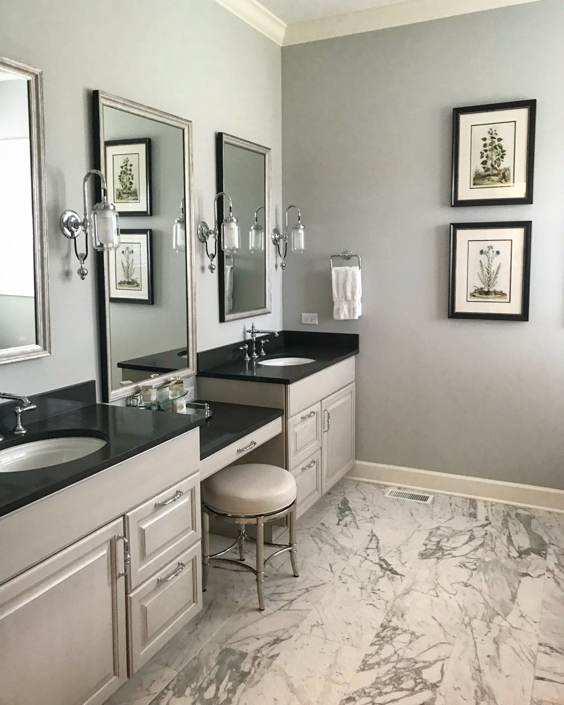 A bathroom with two sinks , two mirrors and a stool.
