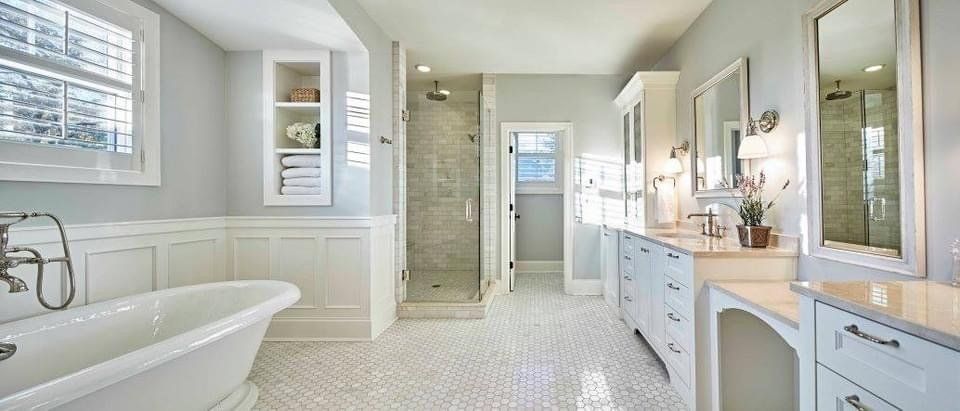 A bathroom with a tub , sinks , mirrors and a walk in shower.