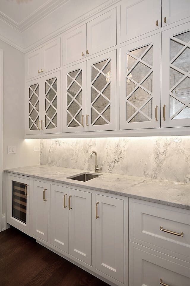A kitchen with white cabinets and marble counter tops and a sink.