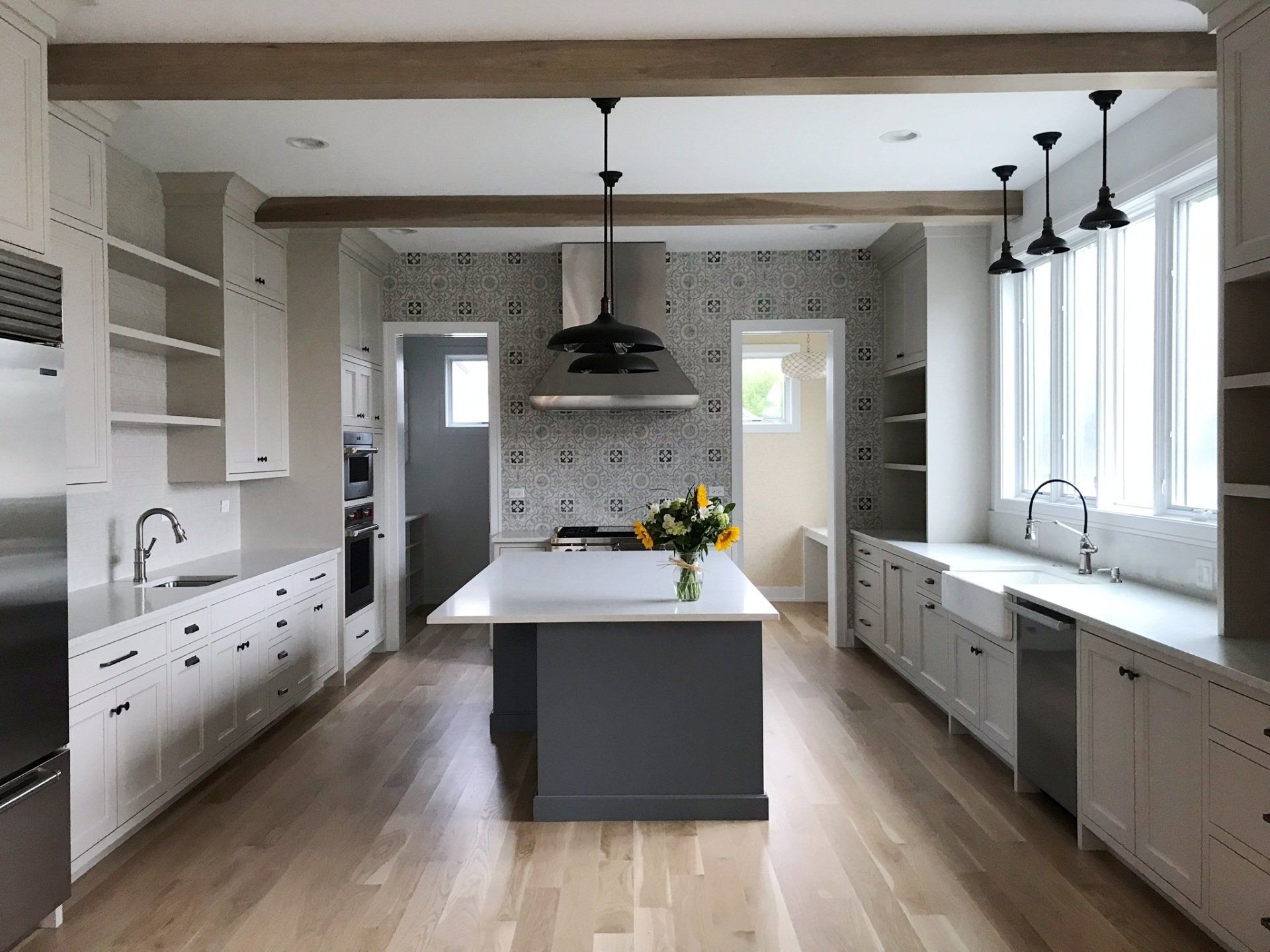 A kitchen with white cabinets and stainless steel appliances and a large island in the middle.