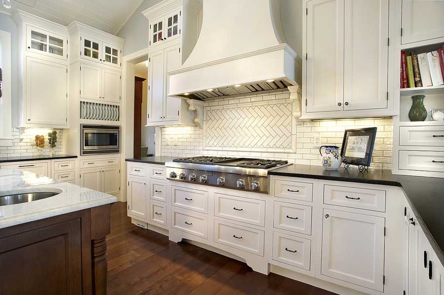 A kitchen with white cabinets and a stove top oven