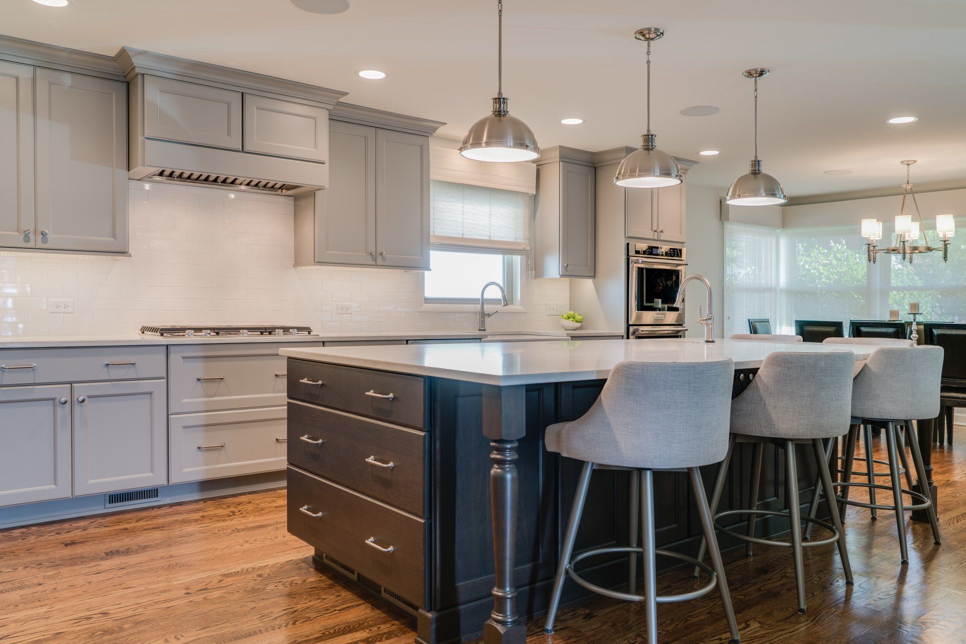 A kitchen with a large island and stools in it.