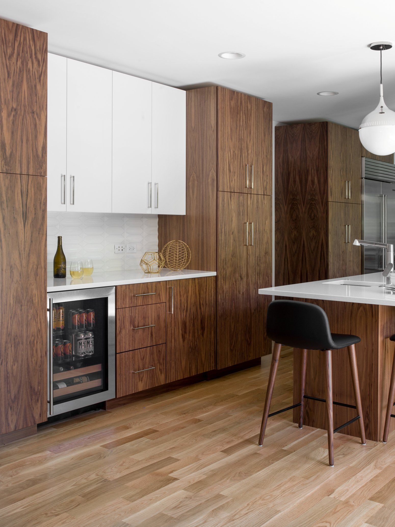 A kitchen with wooden cabinets , a refrigerator , a sink , and a bar.