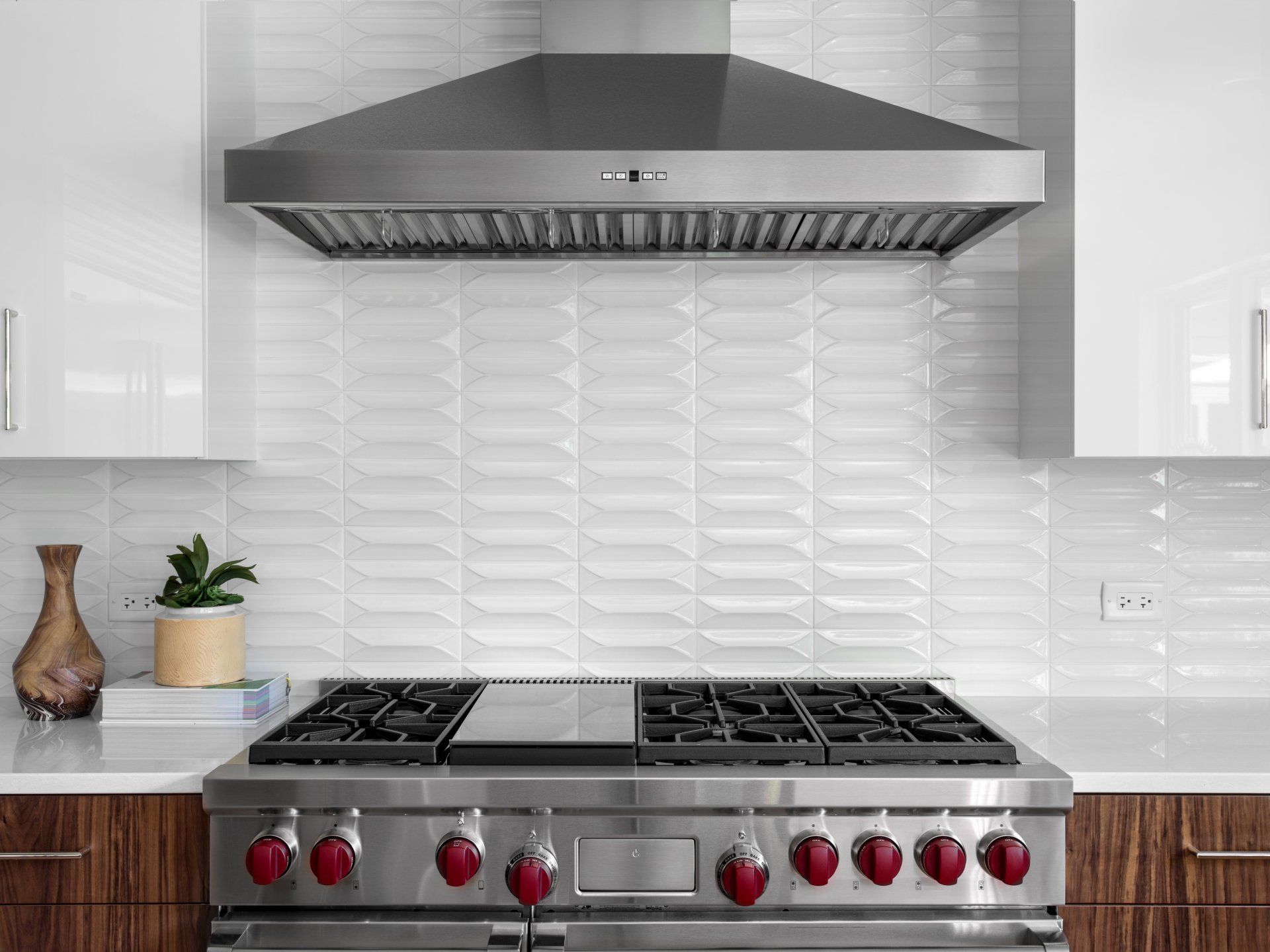 A kitchen with a stove top oven and a hood above it.