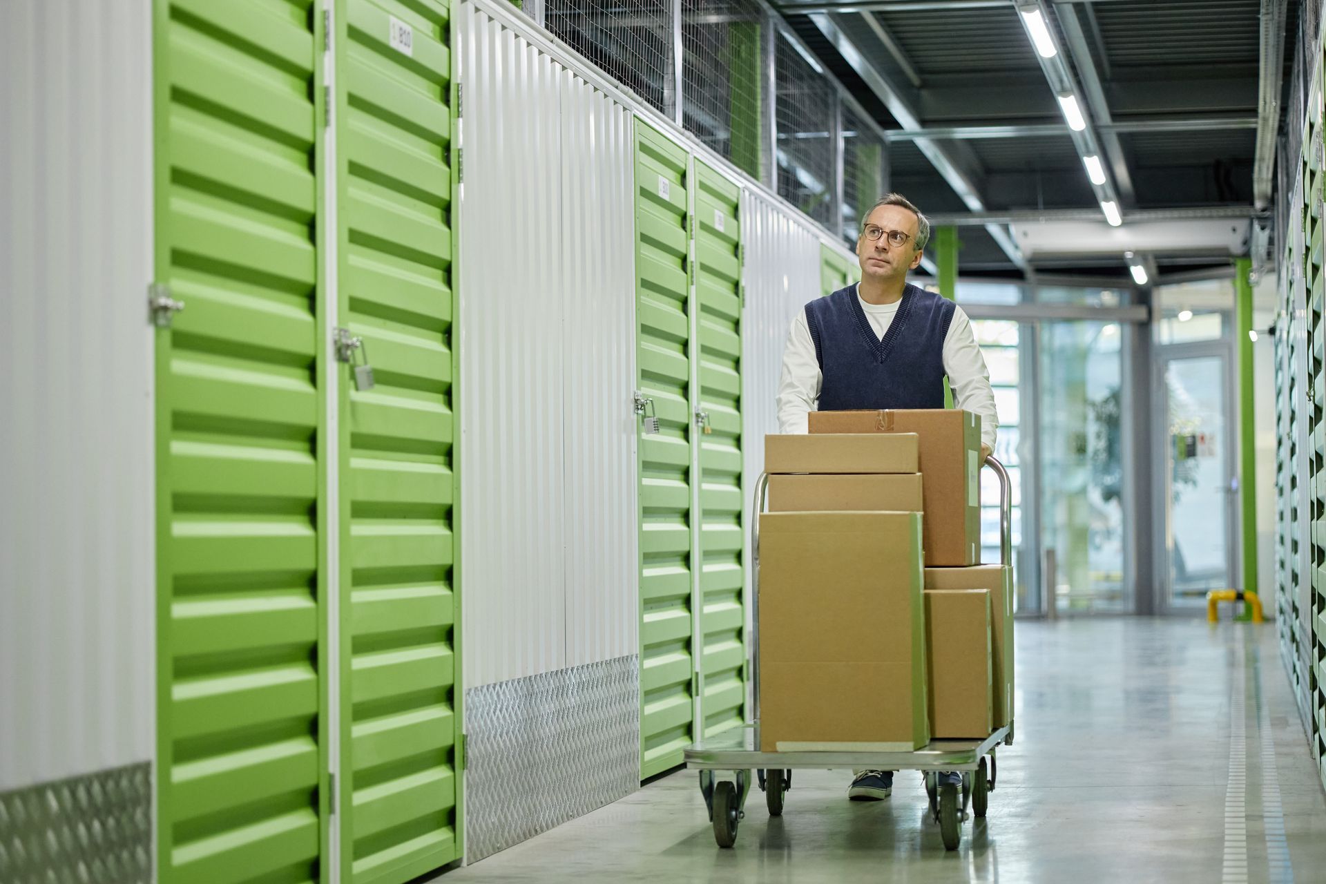 Worker moving boxes on a cart inside business storage units. Worker moving boxes on a cart inside business storage units.