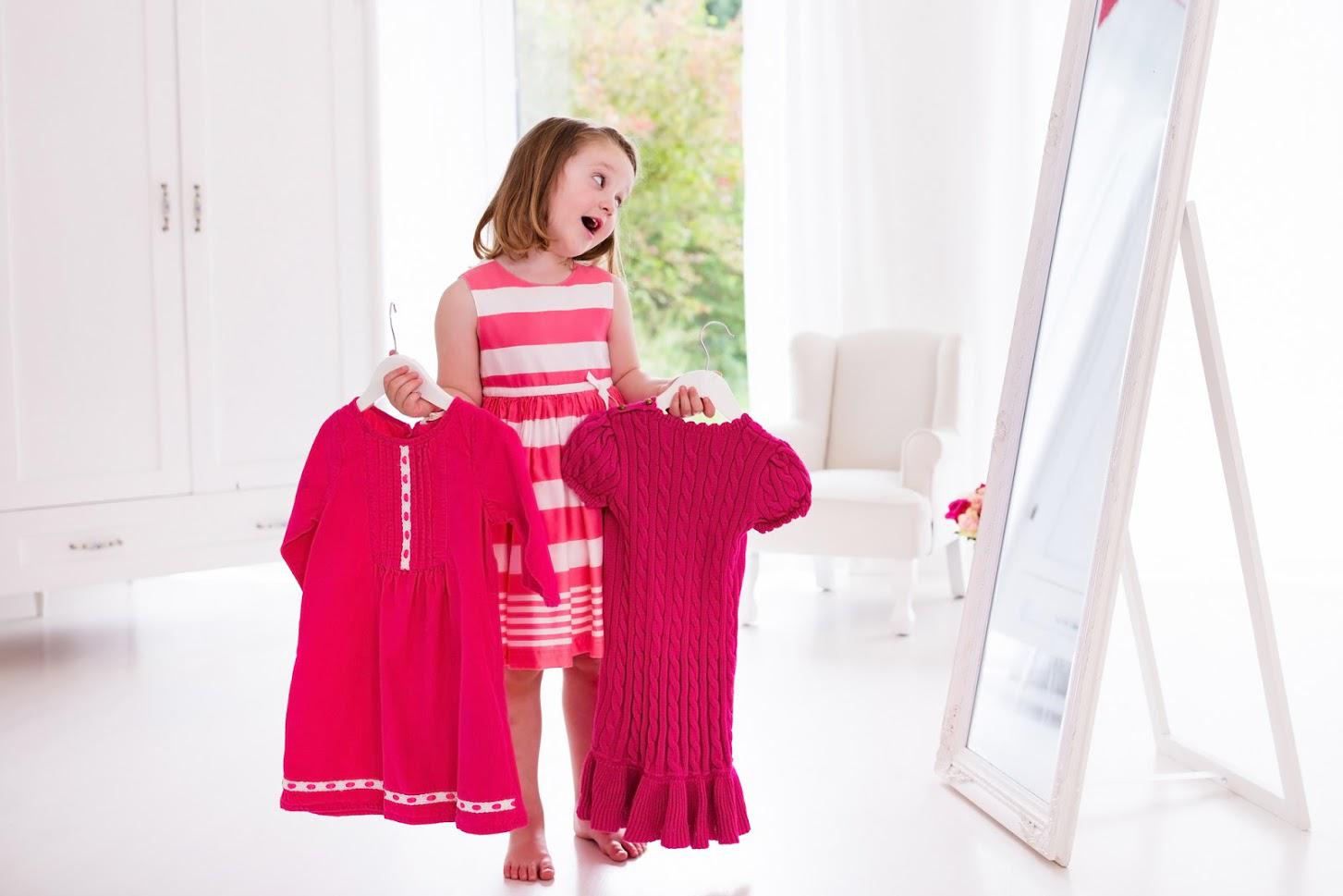 Packing — Child Holding Two Pink Dresses in Vienna, VA