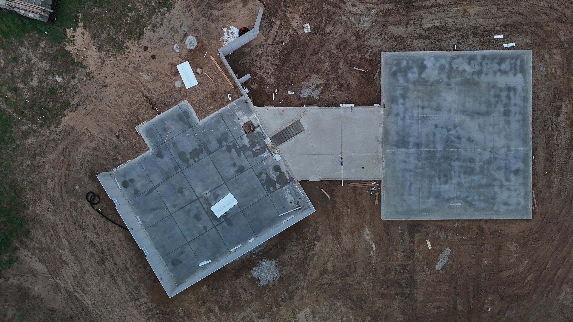 Aerial view of concrete foundations and dirt ground at a construction site.