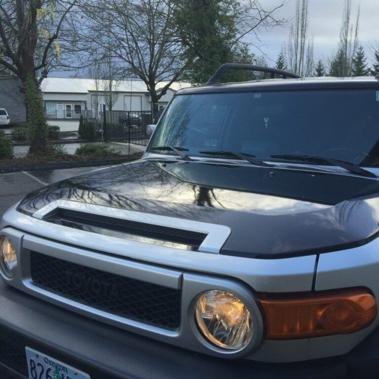 Black SUV parked outdoors with silver trim and round headlights in a residential area