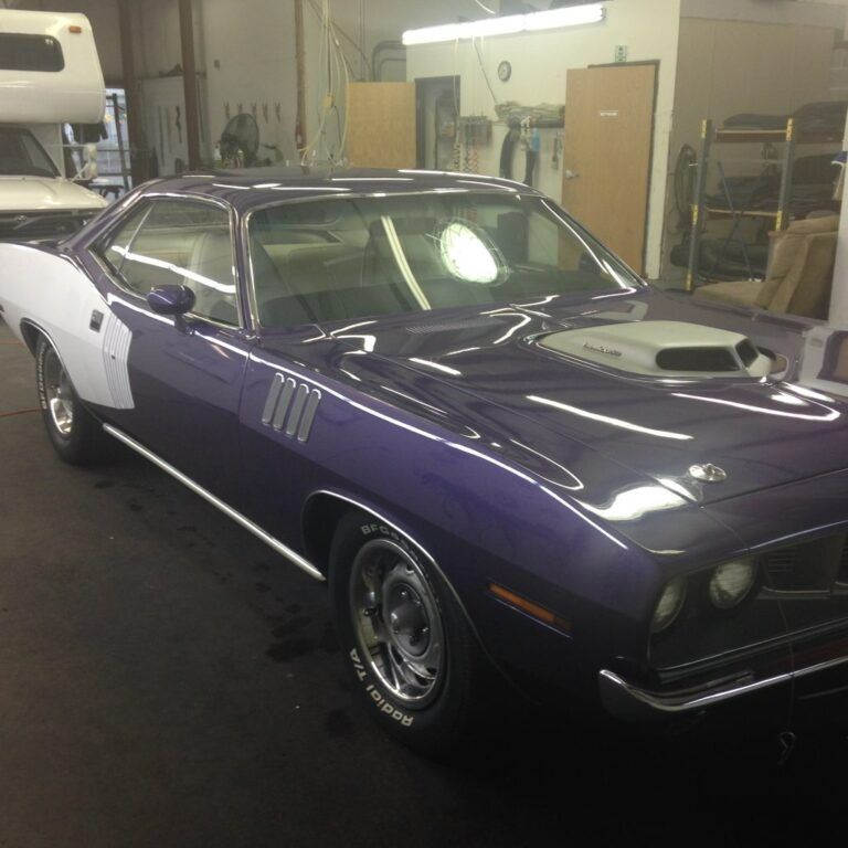 Purple classic muscle car with white side panels parked in a garage