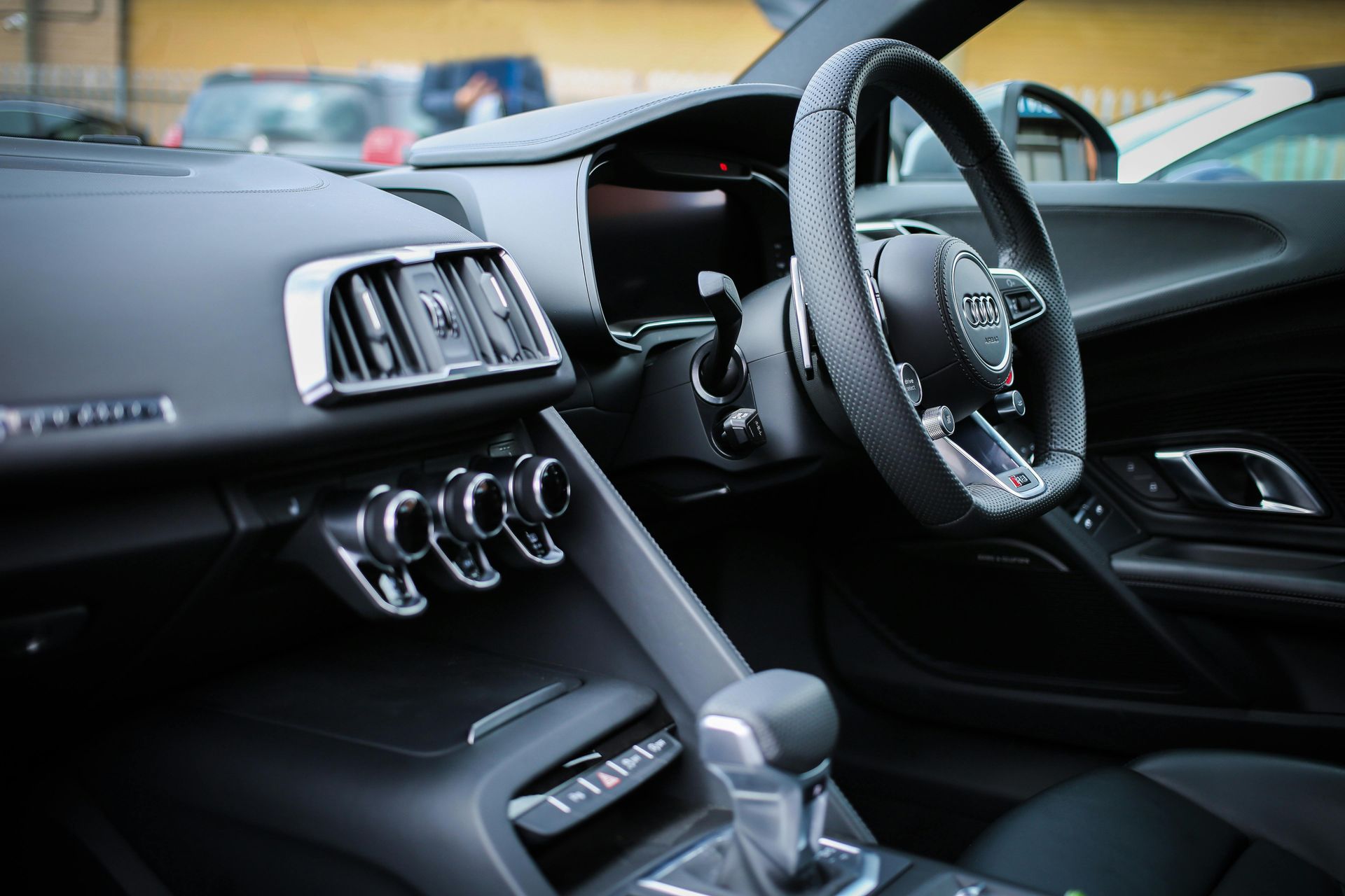 Interior of a luxury sports car featuring a black dashboard, steering wheel, and silver accents.