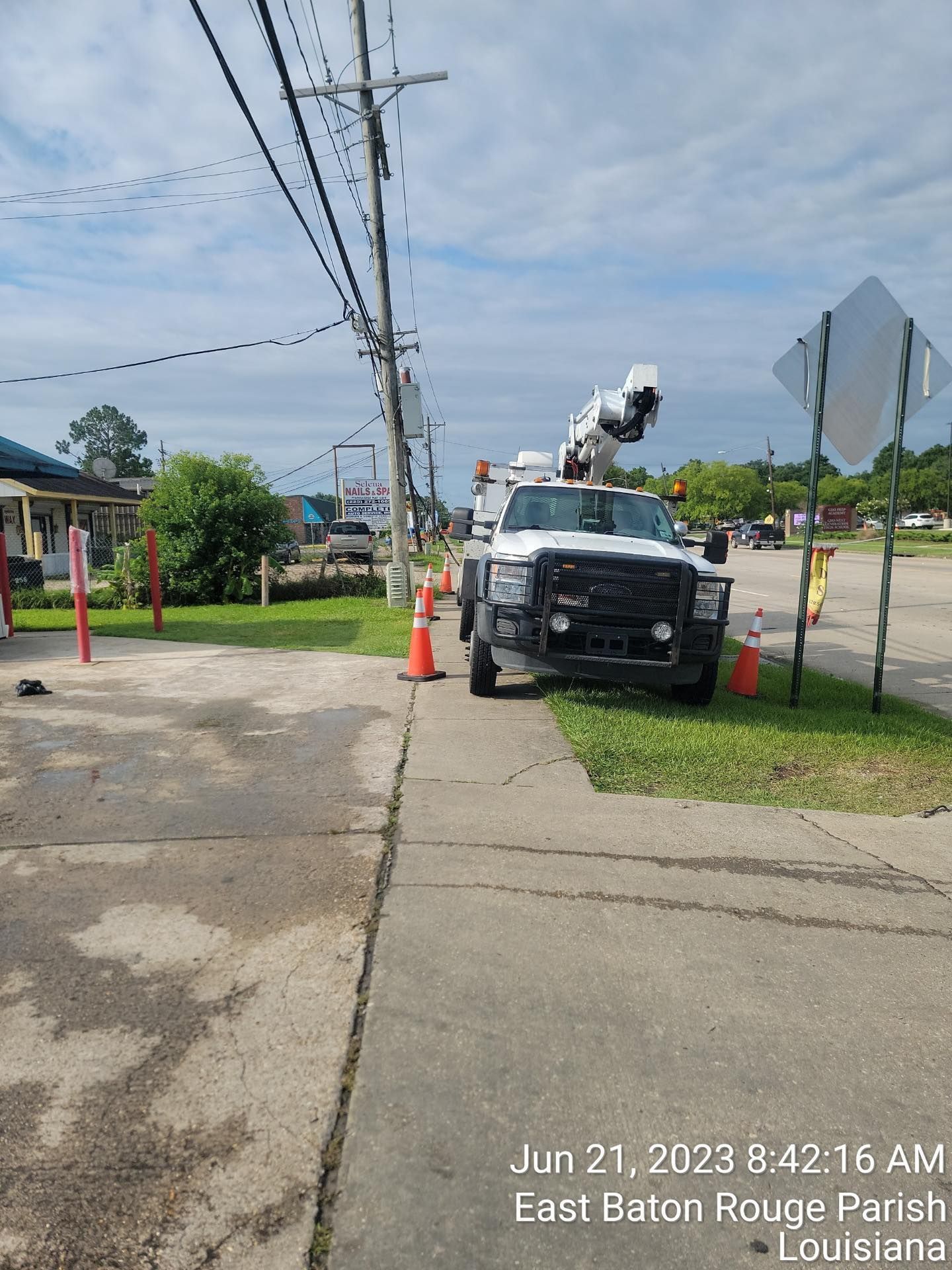 A white truck is parked on the side of the road next to a street sign.