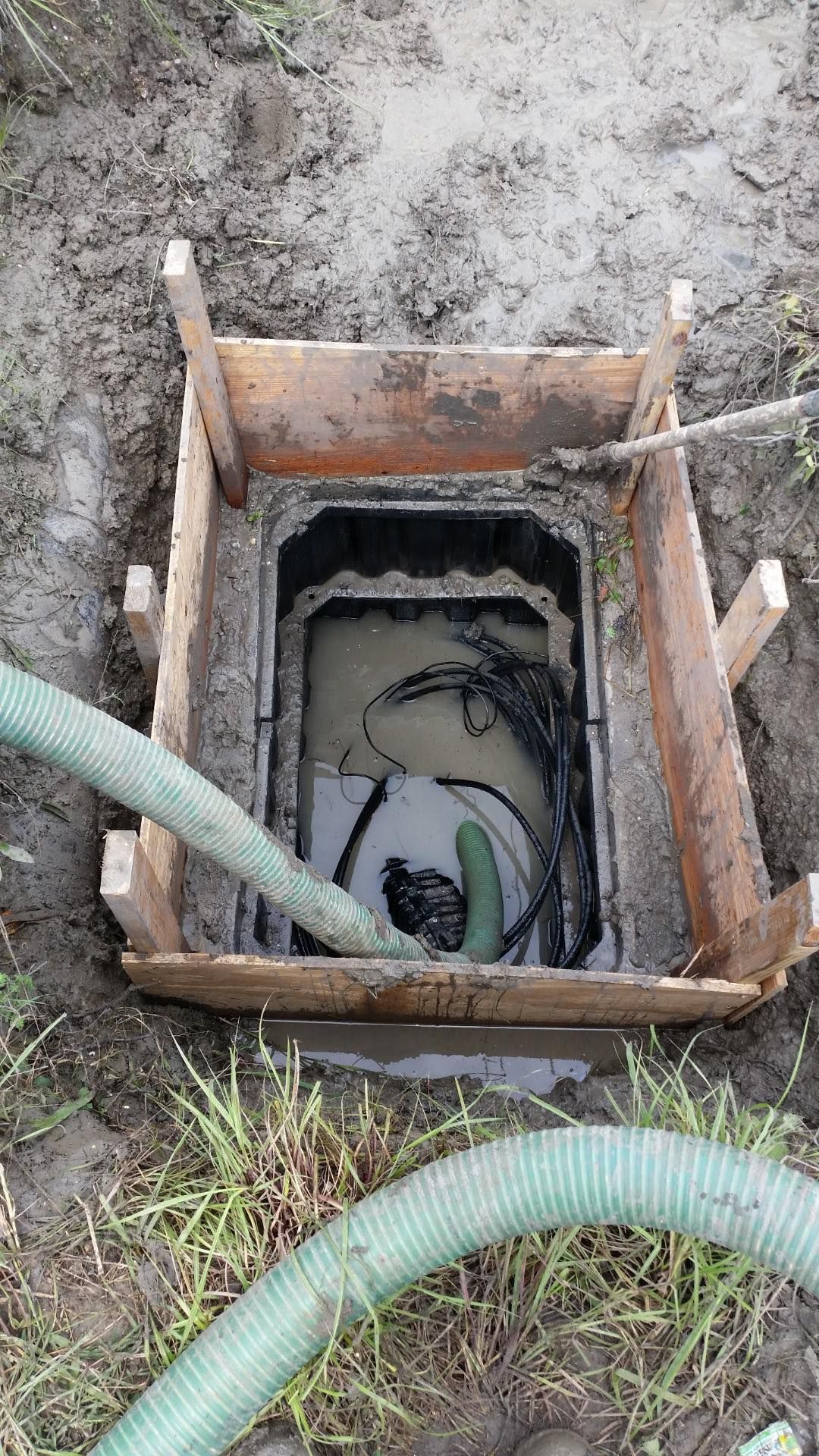 A manhole cover is being filled with water by a green hose.