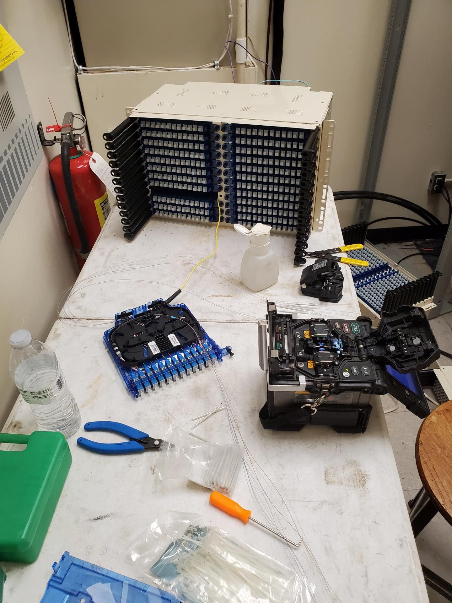 A table with a lot of tools on it and a fire extinguisher on the wall.