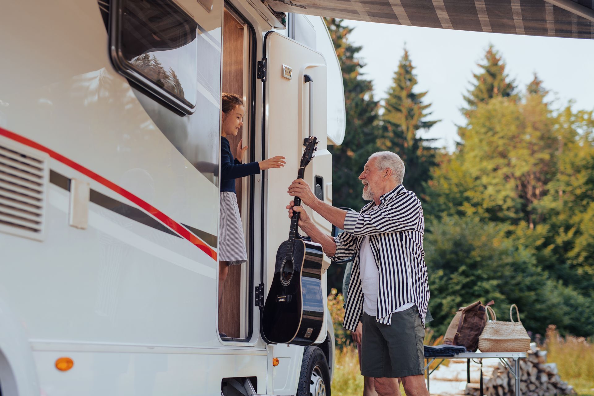 A man is putting a guitar in the back of a rv.