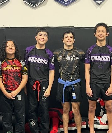 Three men are standing next to each other on a mat in a gym.
