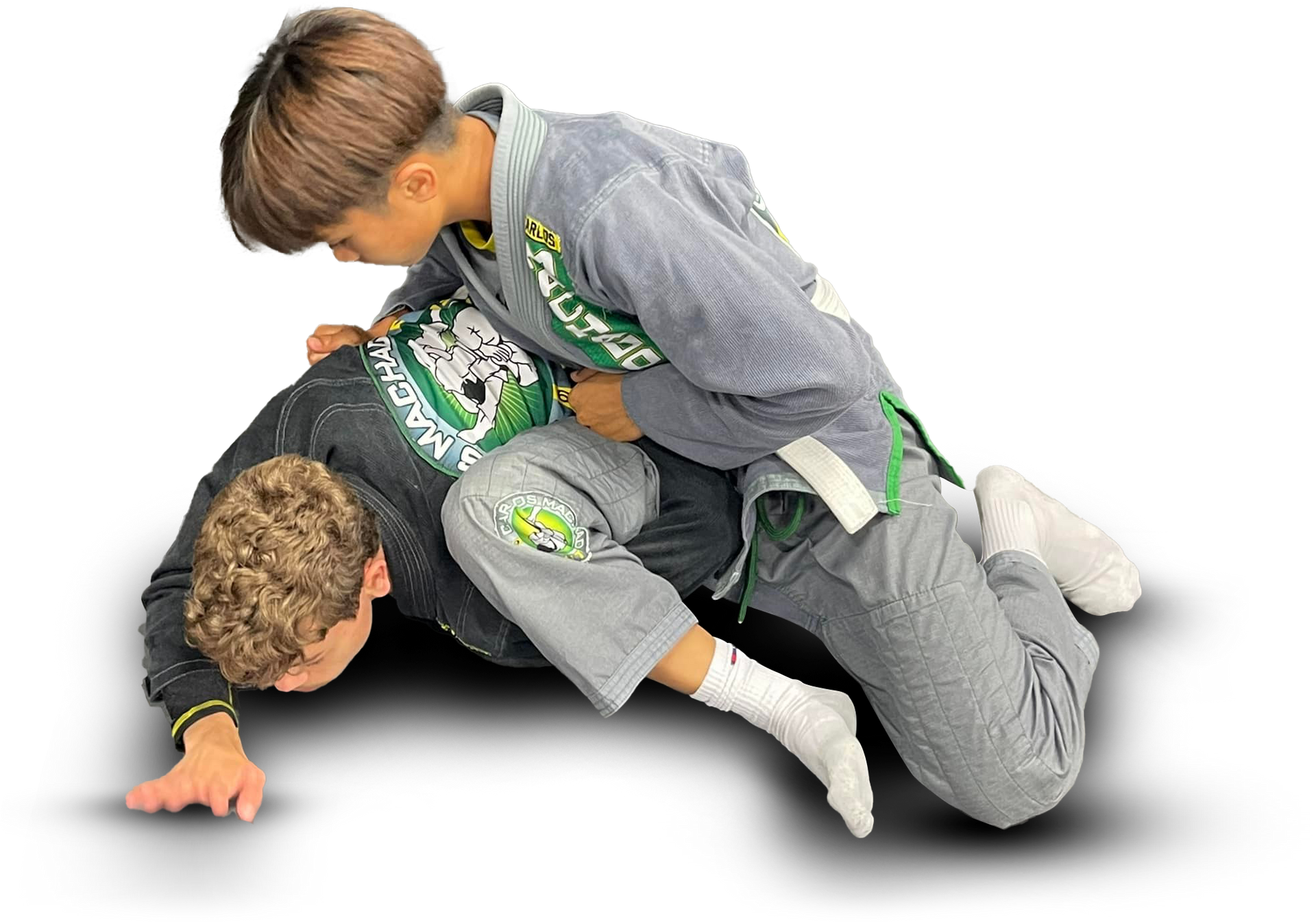Two young boys are wrestling on the ground.
