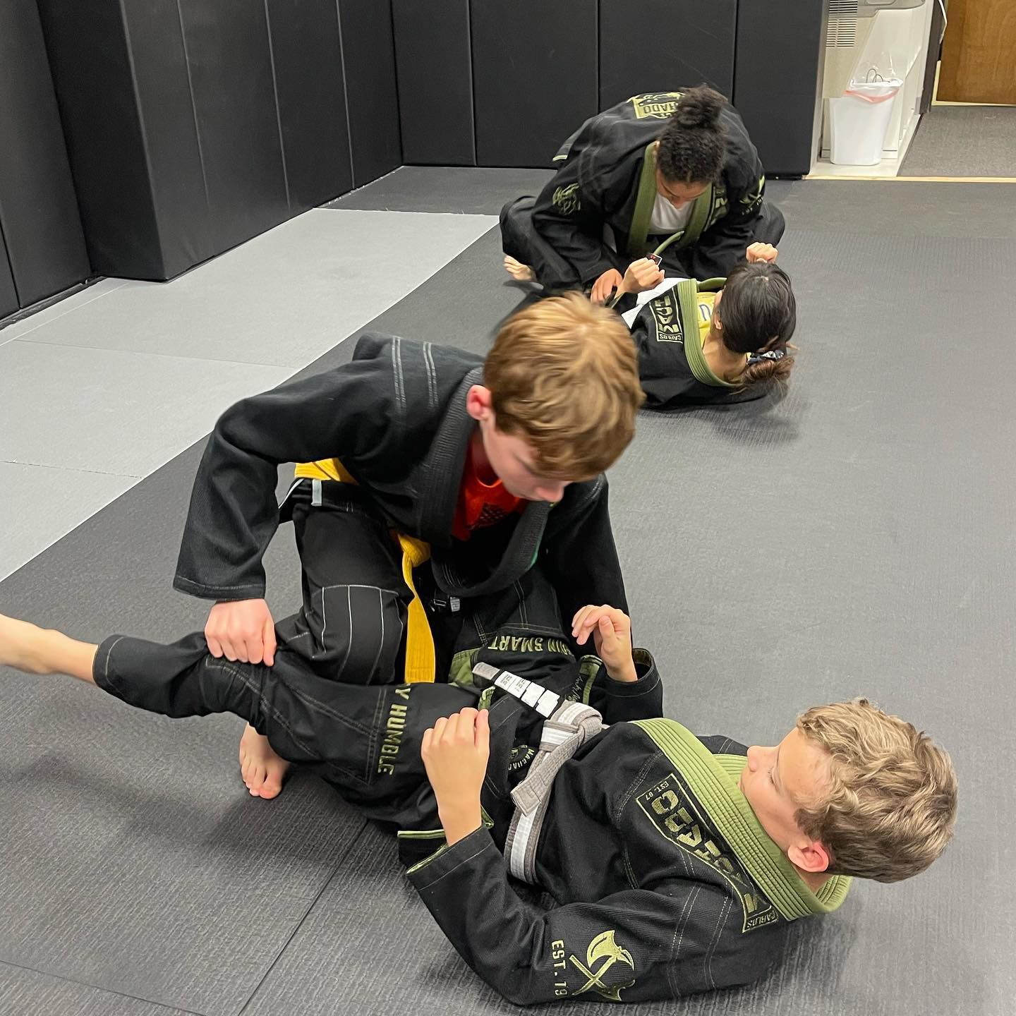 A group of young boys are practicing jiu jitsu on a mat.