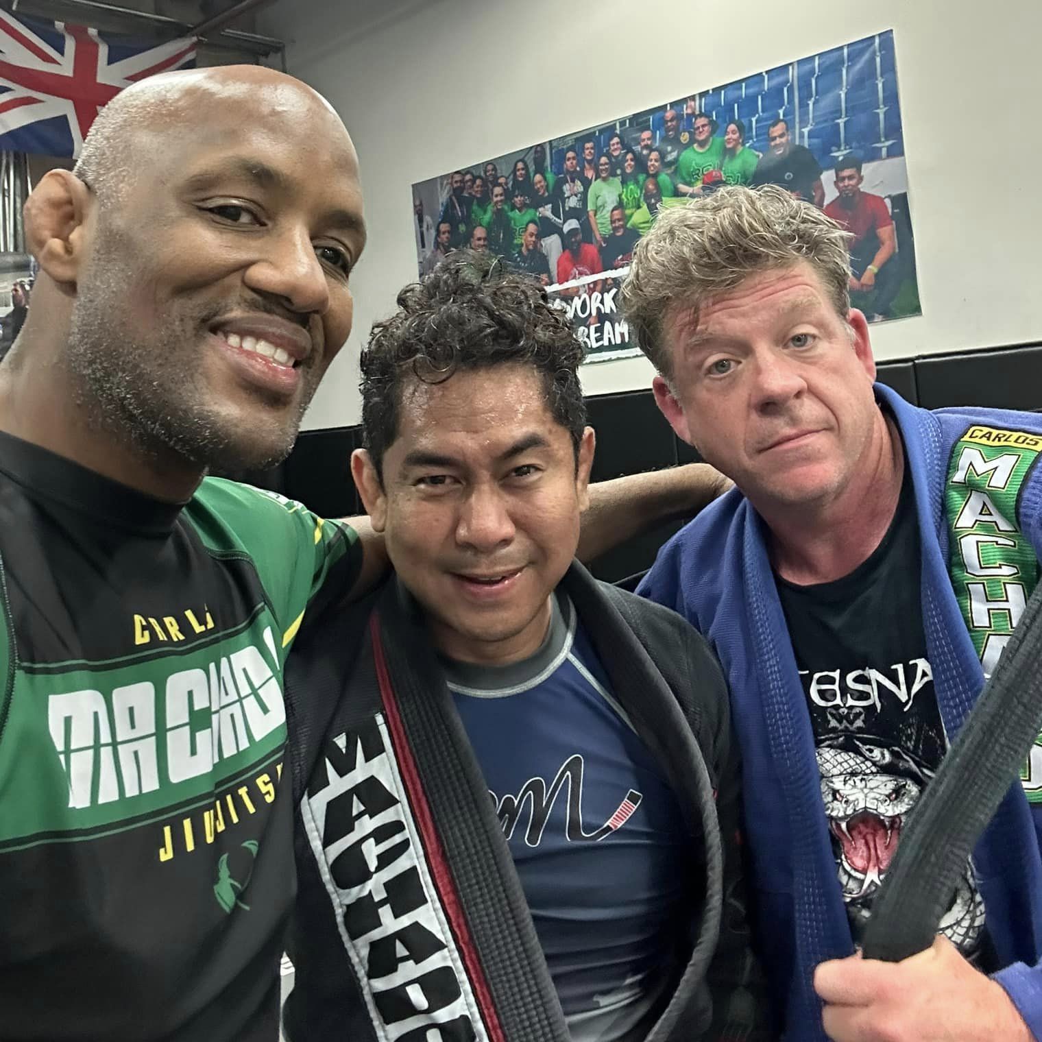 Three men posing for a picture with one wearing a shirt that says jiu-jitsu