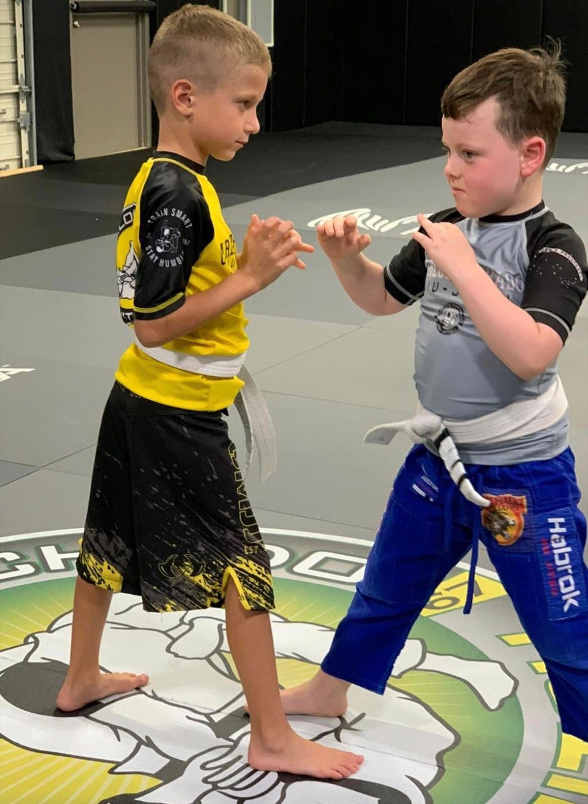 Two young boys are practicing martial arts in a gym.