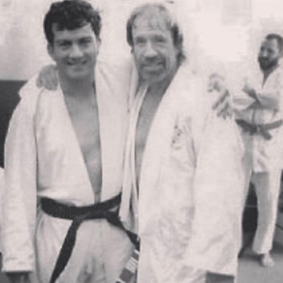 A black and white photo of two men in karate uniforms posing for a picture.
