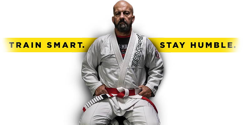 A man in a karate uniform is sitting on a stool with a red belt.