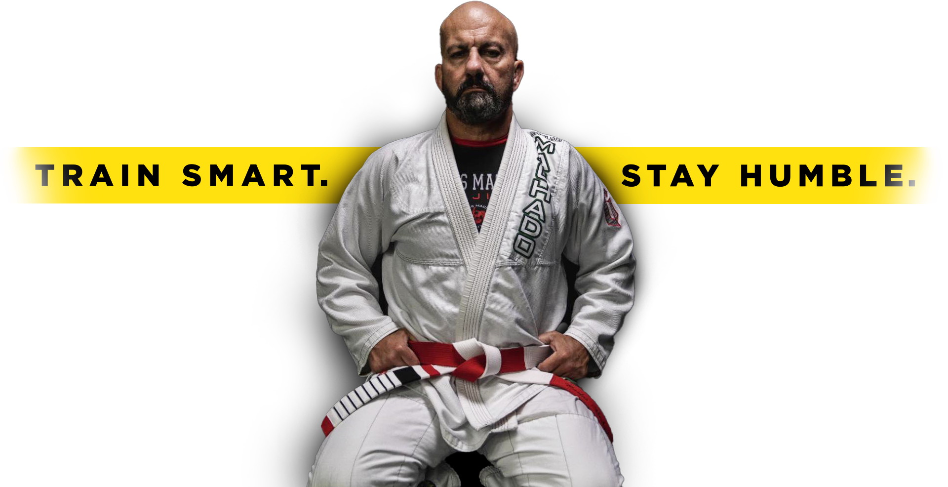 A man in a karate uniform is sitting on a stool with a red belt.