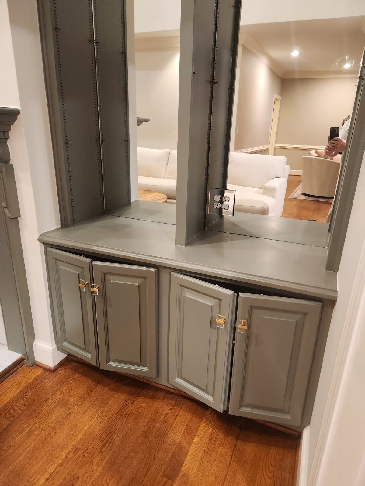 A hallway with gray cabinets and a large mirror.