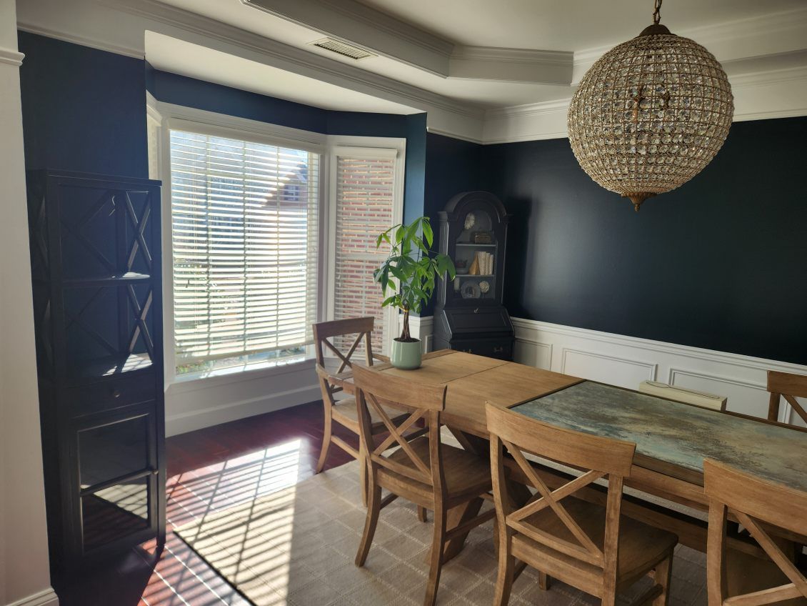 A dining room with a table and chairs and a chandelier hanging from the ceiling.