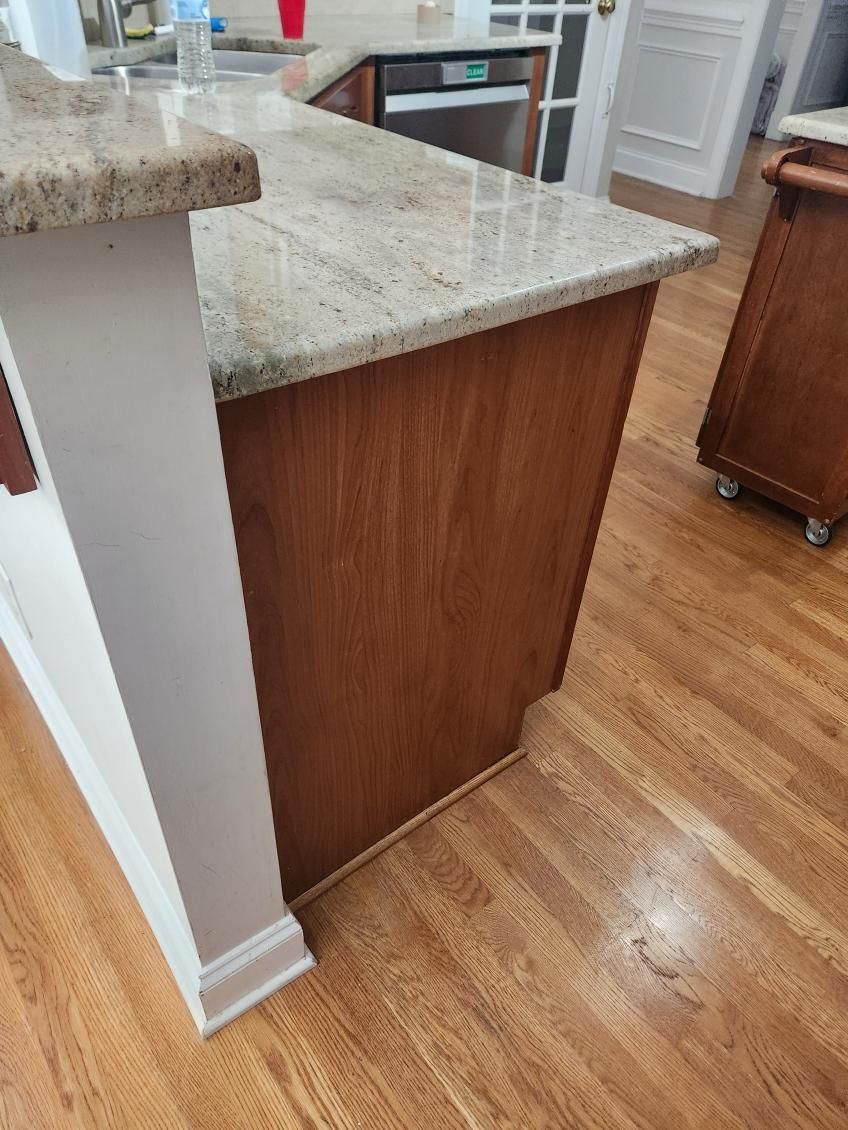 A kitchen with a granite counter top and wooden cabinets.