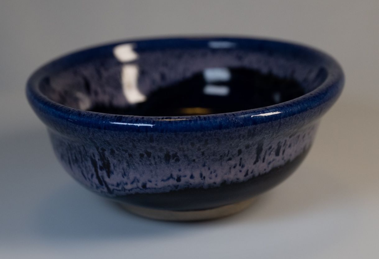 Blue and purple glazed ceramic bowl on a neutral background.