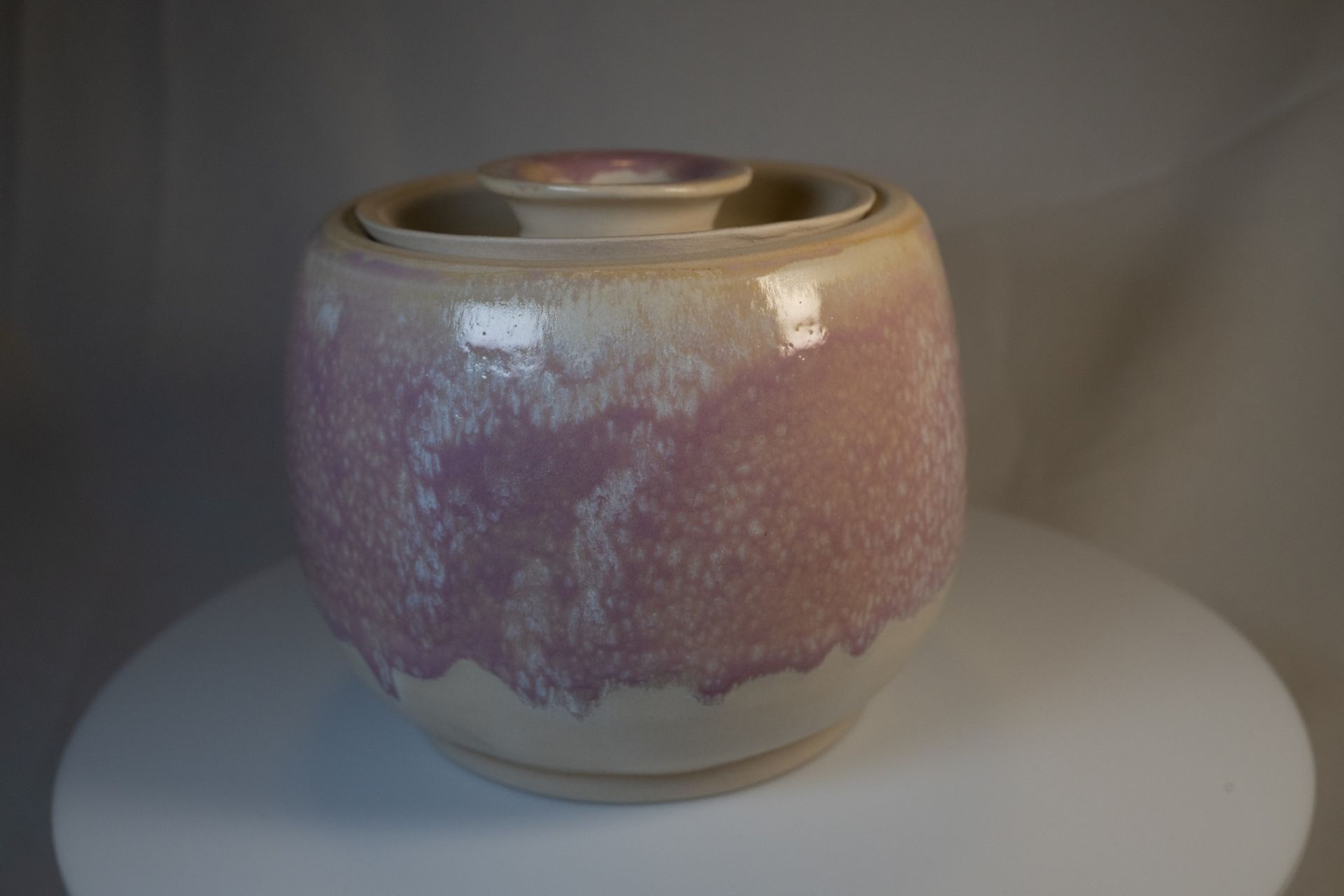 Ceramic jar with lid, lavender and cream glazed finish, set on white surface.