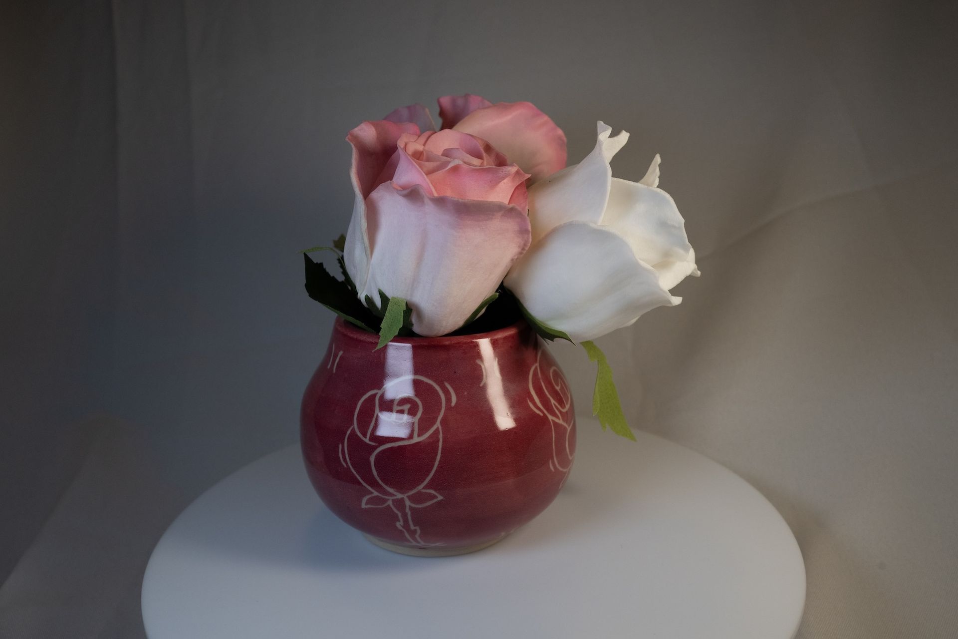 Red vase with roses; white and pink blooms.