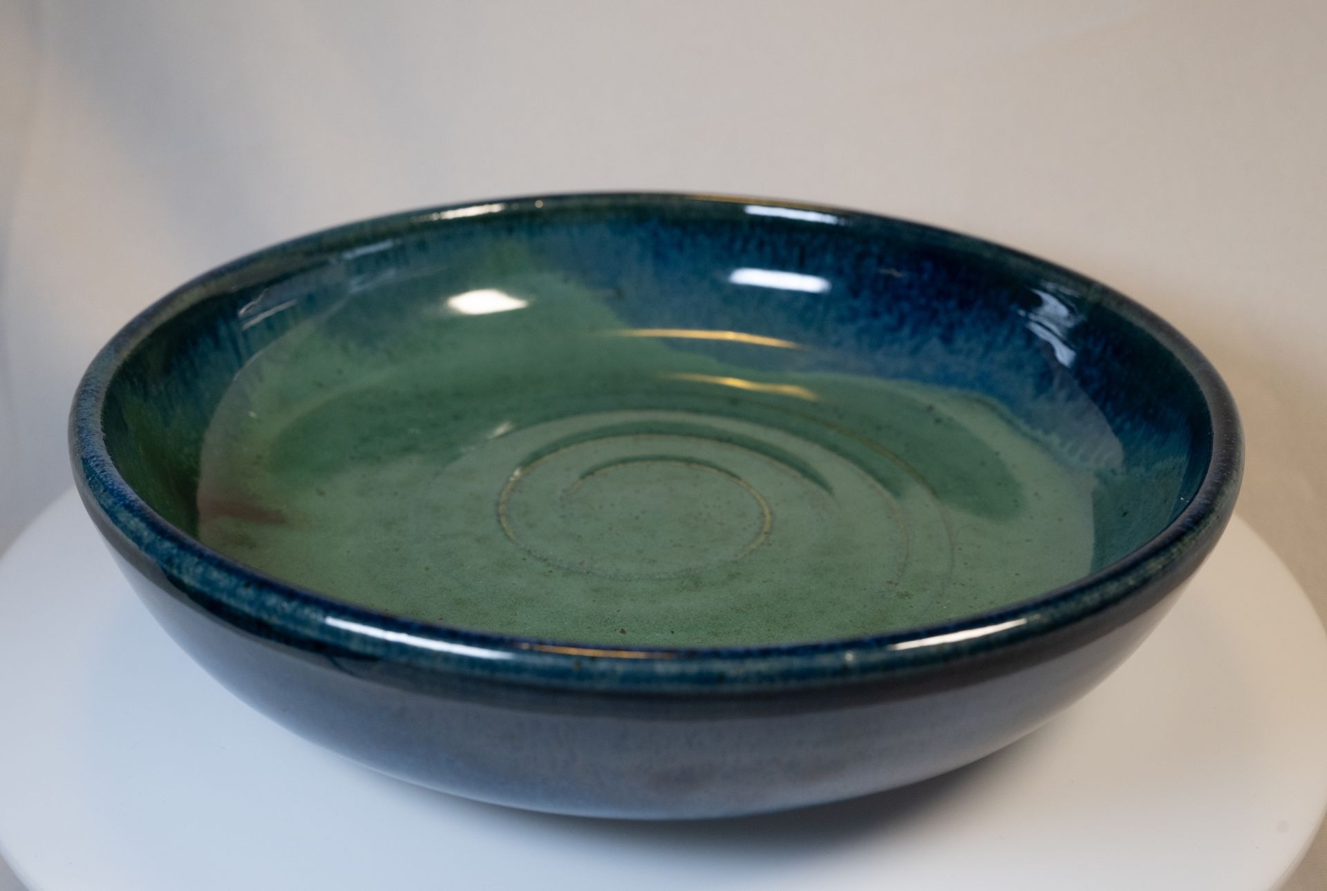 Ceramic bowl with gradient blue to green glaze, on a white surface.
