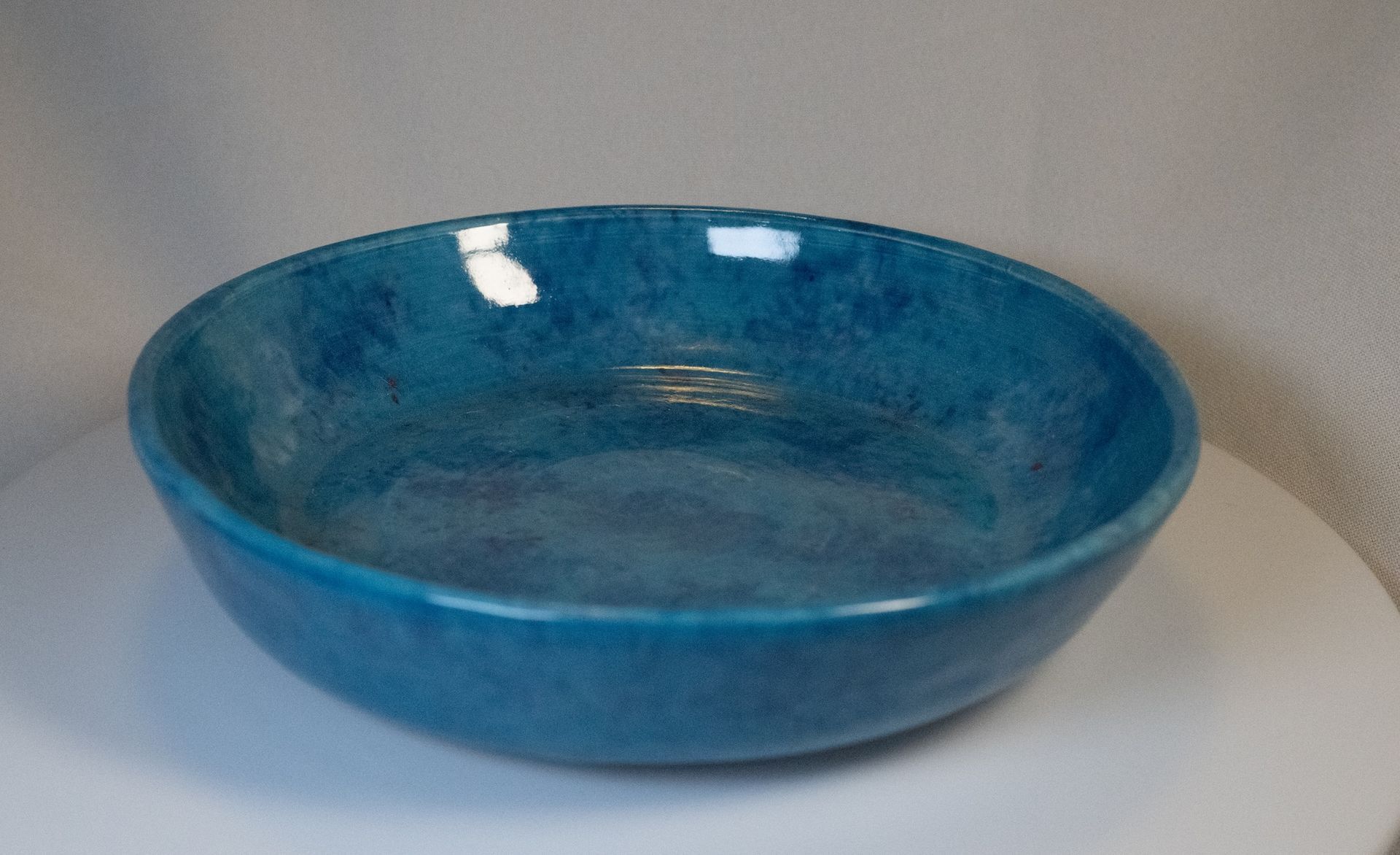 Blue ceramic bowl on a white surface, with a glossy, textured interior.