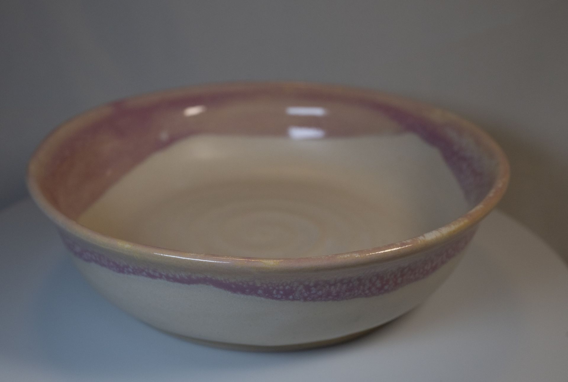 Ceramic bowl with white interior and a lavender-colored rim and exterior.