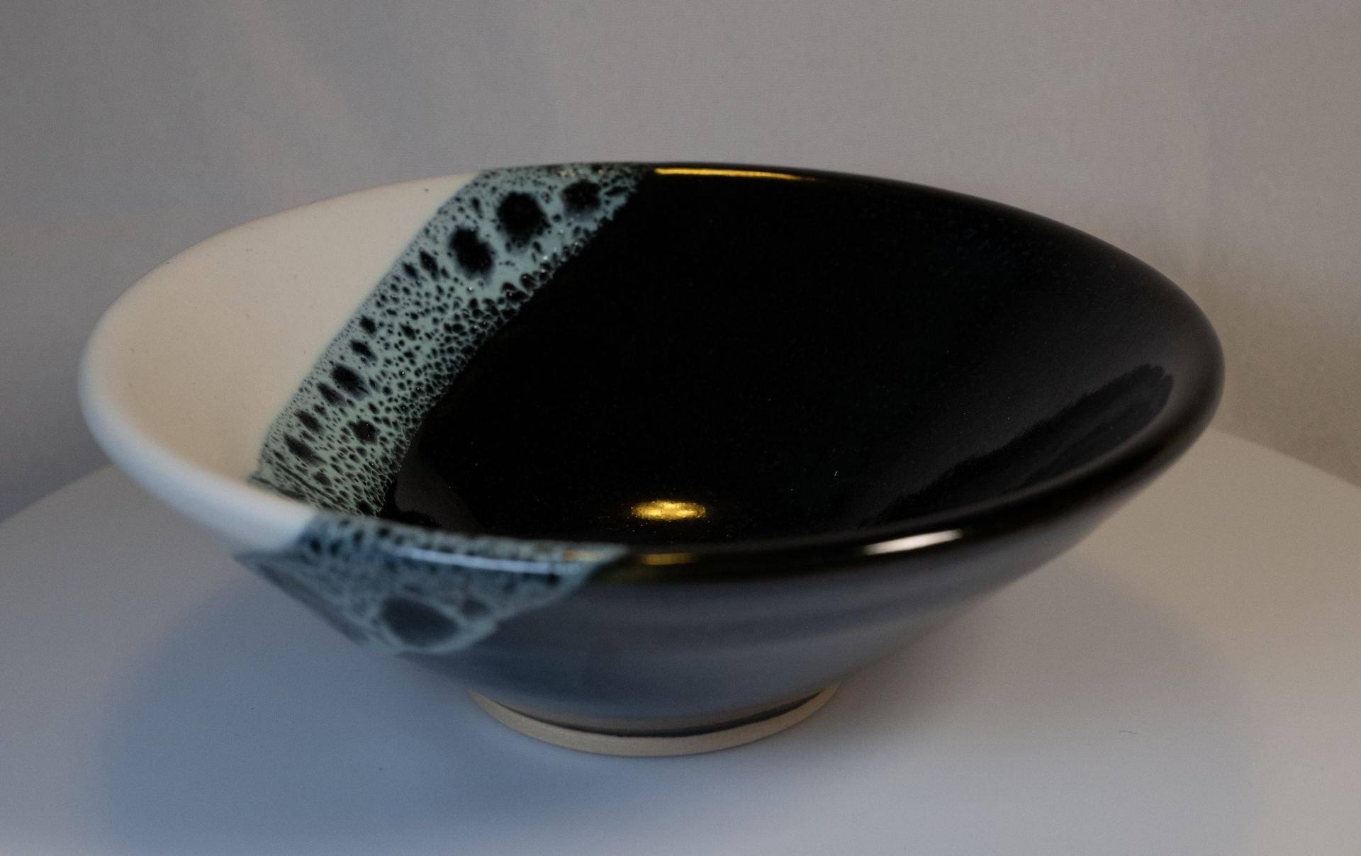 Ceramic bowl, diagonally divided: white and black with a speckled blue-green area.