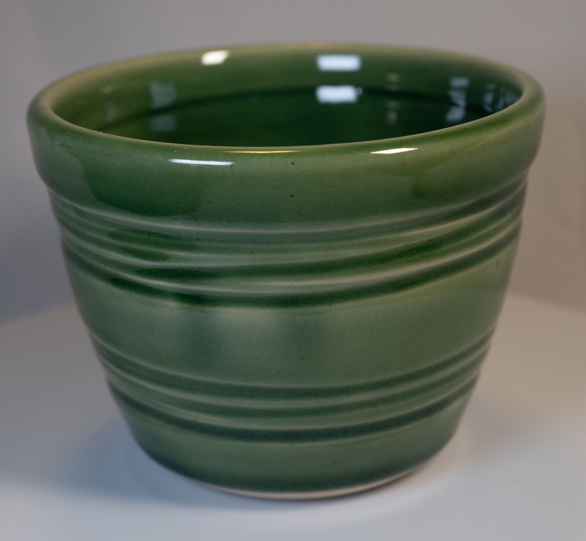 Green ceramic pot with horizontal ridges.