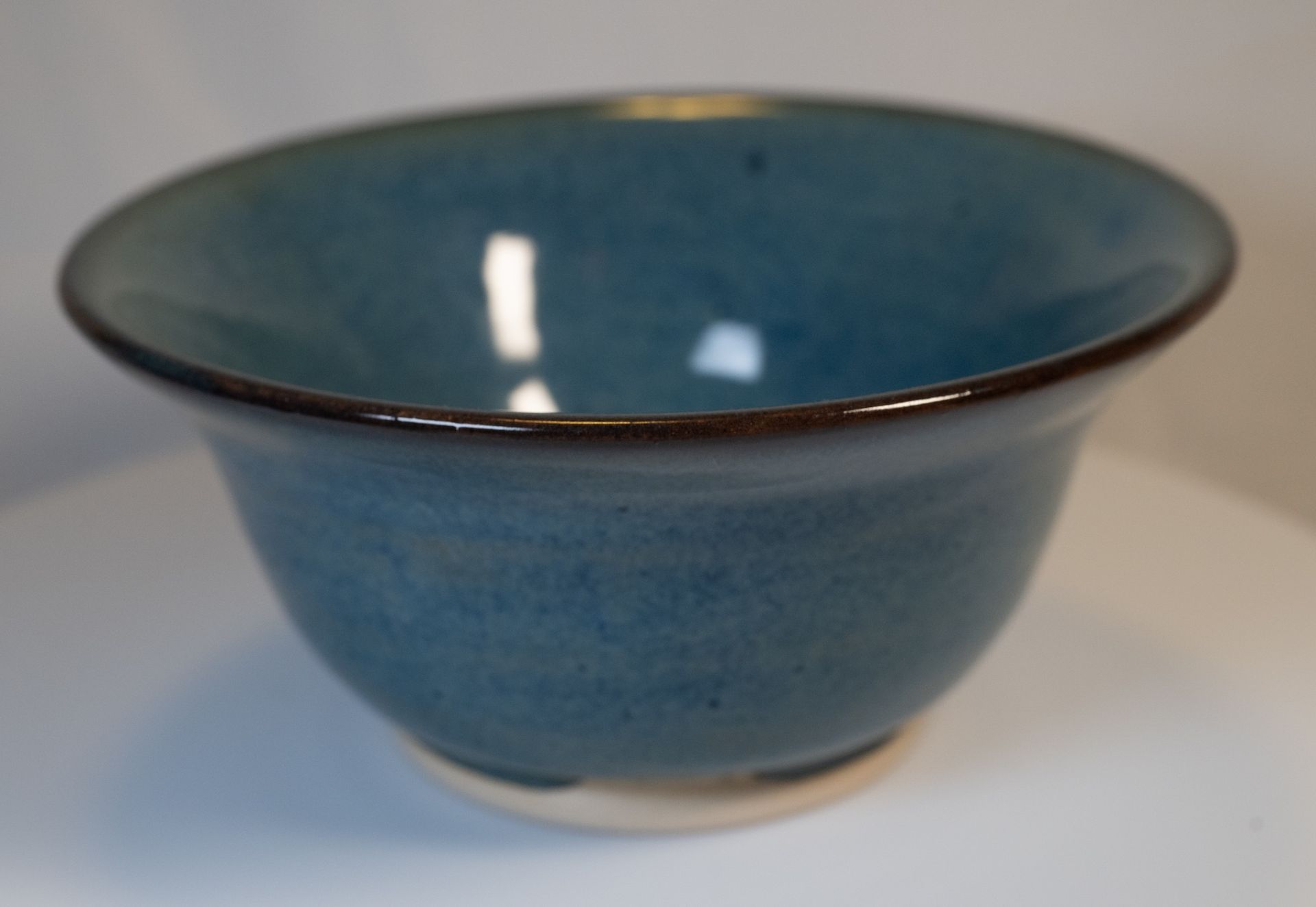 Blue ceramic bowl, with a dark brown rim, on a white surface.