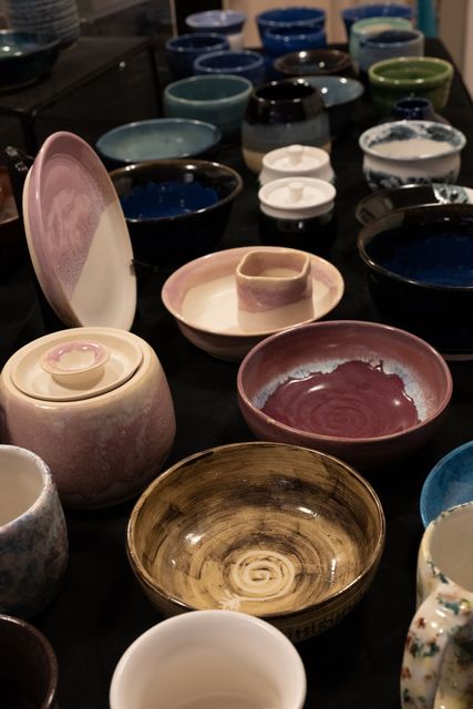 Ceramic bowls and dishes on display, various colors and styles, dark surface.