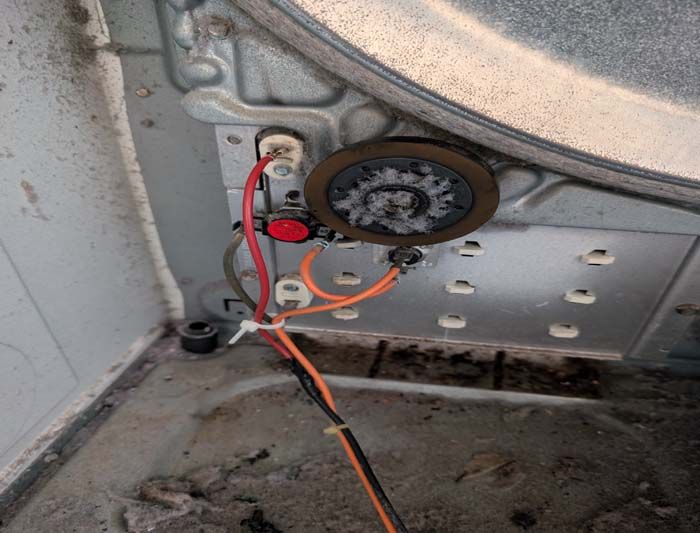 Inside of a dryer drum, electrical components are visible, including a thermal fuse and wiring.