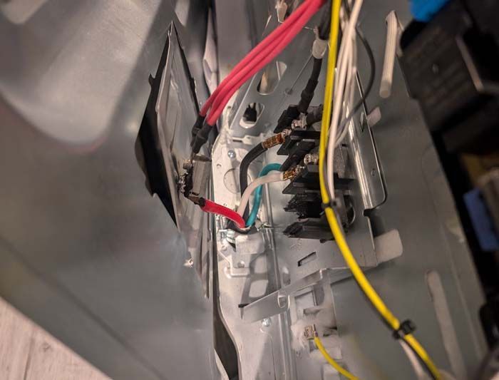 Damaged appliance wiring, red and yellow wires, within a metal appliance housing.