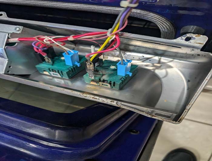 Inside a blue oven: two green control switches with colored wires attached.