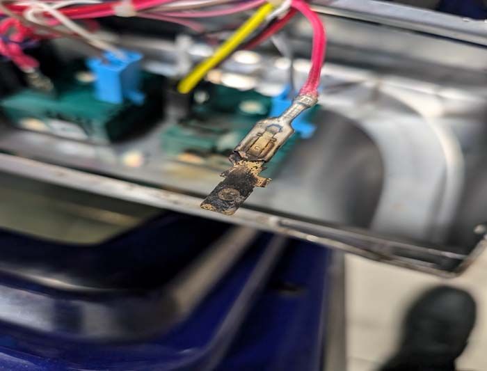 Burnt wire terminal connected to a circuit board inside an appliance.